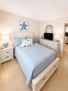 a bedroom with a large bed with blue sheets and a tv at Beach Palms- Unit 102 in Clearwater Beach +26 photos