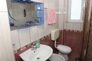 a bathroom with a white sink and a toilet at Evelin Apartment Berat in Berat +17 photos
