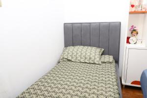 a bed with a gray headboard and a pillow at Evelin Apartment Berat in Berat