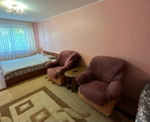 a living room with two chairs and a bed at Nice Apartment in Kyiv