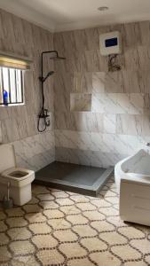 a bathroom with a shower and a toilet and a sink at The Nest Homes in Abuja