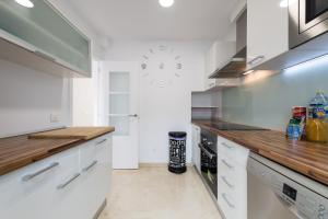 eine Küche mit weißen Schränken und einer Uhr an der Wand in der Unterkunft Ilusión in La Playa de Tauro