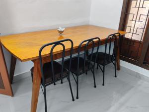 a wooden table with two black chairs around it at Amma's Homestay in Jaffna