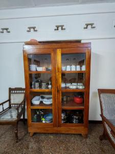 a wooden cabinet with plates and dishes in it at Amma's Homestay in Jaffna +13 photos