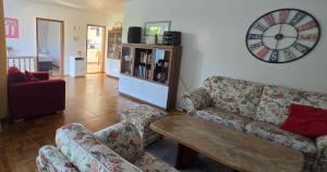 a living room with a couch and a clock on the wall at Ferienwohnung Helena in Markkleeberg