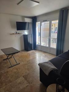 a living room with a couch and a table with a tv at Le sunset in Bandol