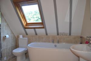 a bathroom with a tub and a toilet and a window at The School House B & B in Bucknell