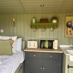 a kitchen with a bed and a microwave on a counter at Shepherds Hut in Shropshire with Swimming Pool in Shifnal