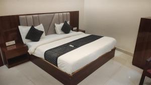 a bedroom with a large bed with black and white pillows at Hotel Grand Taj Pride in Tājganj