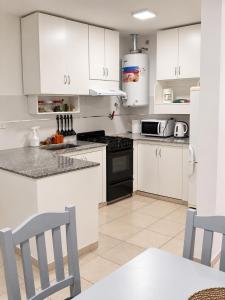 a kitchen with white cabinets and black appliances at Departamento Centro Viedma in Viedma