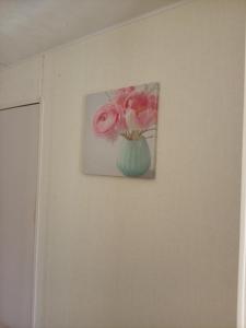 a painting of pink roses in a vase on a wall at Lucy retreat in Great Driffield +5 photos
