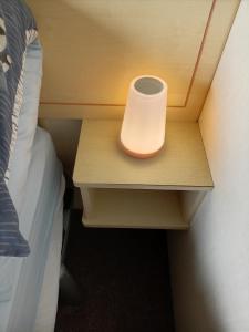 a light on a night stand next to a bed at Lucy retreat in Great Driffield