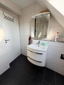 a white bathroom with a sink and a mirror at Lenyanca Apartment in Salzbergen