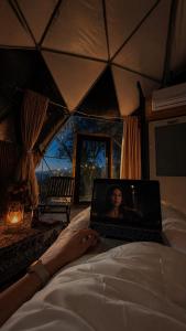 a woman laying on a bed with a laptop at AL-hakoura in Mas'ada
