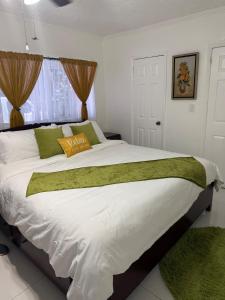 a bedroom with a large white bed with green pillows at Your Blooming Getaway in Nassau