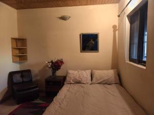 a bedroom with a bed and a chair and a window at Naqvi House in Murree