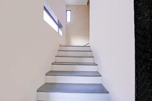a staircase in a house with white walls and a window at Super Townhouse LIG Main Road Indore in Indore