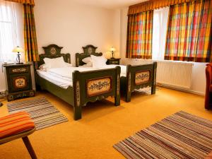a bedroom with two beds and two tables and curtains at Hotel Tilman Riemenschneider by ANS in Rothenburg ob der Tauber