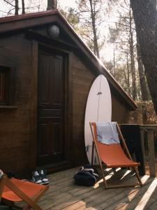a chair and a surfboard in front of a cabin at Auberge Aparra Surfcamp Ondres in Ondres