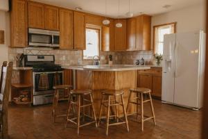 a kitchen with wooden cabinets and a white refrigerator at El Ranchito Alegre Private 3BR Home in Historic Corrales in Corrales