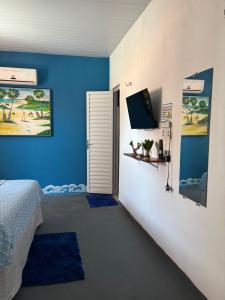 a bedroom with blue walls and a tv on the wall at Casa Cochilo na Rede in Beberibe