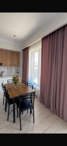 a dining room with a table and chairs and a kitchen at Novel in Korumdy