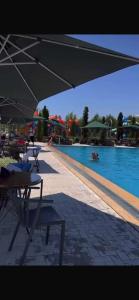a pool with tables and chairs and an umbrella at Novel in Korumdy
