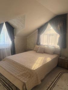 a bedroom with a large bed with two windows at Family Villa in Osh