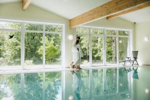 a woman in a white dress walking in a room with a pool at Der Glaserhof - WaldZeitHotel in Lam