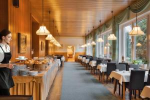 a woman standing in a restaurant with tables and chairs at Der Glaserhof - WaldZeitHotel in Lam