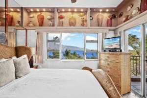 a bedroom with a bed and a tv and windows at Menehune Shores 606 - Direct Ocean Front, Split AC in Kihei +52 photos