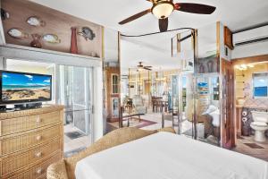 a bedroom with a bed and a tv in a room at Menehune Shores 606 - Direct Ocean Front, Split AC in Kihei