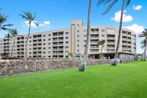a large apartment building with palm trees in a park at Menehune Shores 606 - Direct Ocean Front, Split AC in Kihei