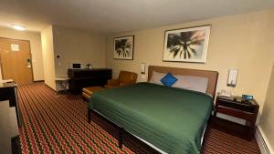 a hotel room with a bed and a chair at Chesaning INN & Suites in Chesaning