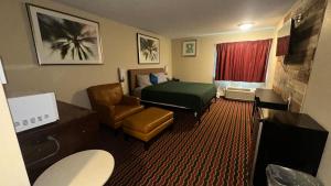 a hotel room with a bed and a chair at Chesaning INN & Suites in Chesaning