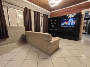 a living room with a couch and a tv at Sitio Chacara Piscina Aquecida Acesso Asfaltado in Juquitiba