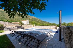 a pool with a table and chairs next to a wall at Luna Pool Apartment in Danilovgrad