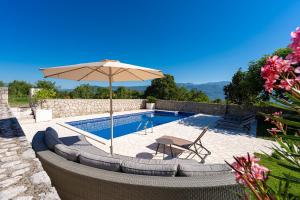 a patio with an umbrella and chairs and a pool at Luna Pool Apartment in Danilovgrad