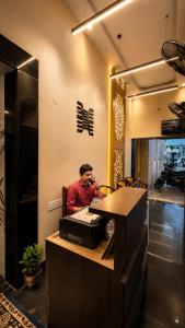 a man sitting at a counter talking on a phone at Hajiyar Residency in Rāmanāthapuram