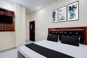 a bedroom with a bed and a tv on the wall at Hotel O Star Light in Rohtak