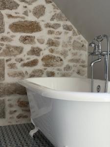 a bath tub in a bathroom with a stone wall at Château Saint Georges in Mauléon