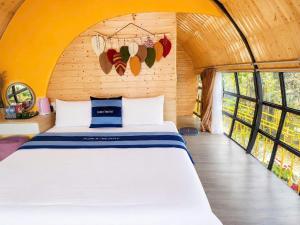 a bedroom with a bed in a room with windows at Plum Hillside Lodge in Dồng Văn