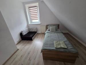 a attic room with two beds and a chair at Cozy Attic Apartment Koszalin in Koszalin
