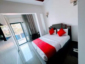 a bedroom with a bed with red pillows and a window at Comfort Deluxe Apart in Kigali +7 photos