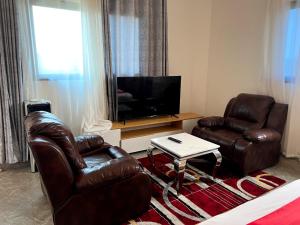 a living room with two leather chairs and a flat screen tv at Comfort Deluxe Apart in Kigali