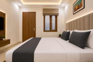 a bedroom with a large white bed with black pillows at Collection O Guru Nanak Dev University Amritsar Formerly Hotel Tashi in Amritsar +16 photos