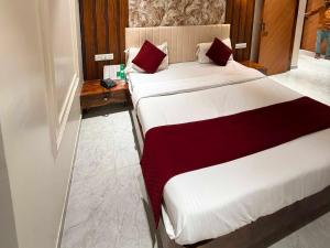 two beds in a hotel room with red and white sheets at Collection O Sunset Point Pangari Formerly Riveria in Mahabaleshwar