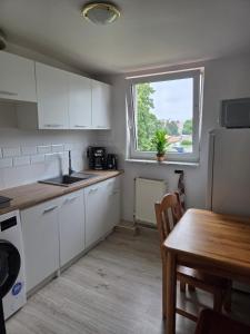 a kitchen with white cabinets and a table and a window at Cozy Attic Apartment Koszalin in Koszalin