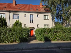a large white house with a red door at Cozy Attic Apartment Koszalin in Koszalin