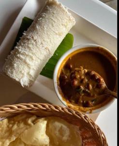 a plate of food with a bowl of soup and bread at Mud apples stay in Varkala +35 photos